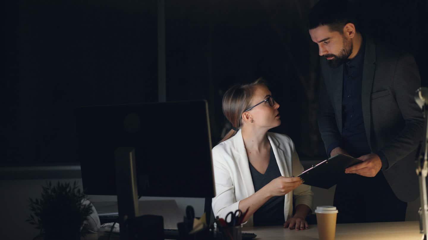Professionisti aziendali che discutono documenti a una scrivania a tarda notte.