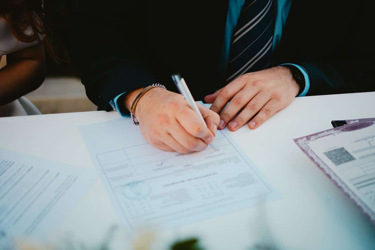 Un uomo in giacca e cravatta firma un contratto su un tavolo.